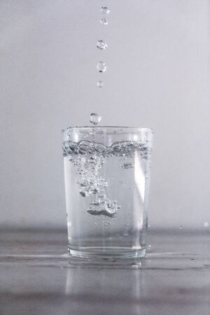 Throwing water into a glass of water on a white background. Drink macro photographyの写真素材
