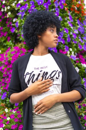 Street style, Dominican girl with afro black hair in some city flowers looking to the rightの写真素材