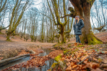 lifestyle, Caucasian blonde in long black coat and wool hat in a forest in autumn