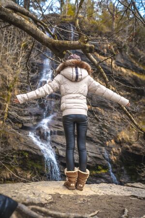 A young woman on her back with jacket in winter at a waterfallの写真素材