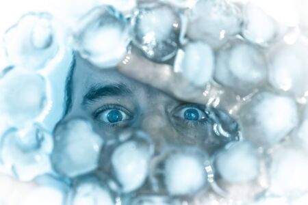 Male face in ice cubes, simulation of freezingの写真素材