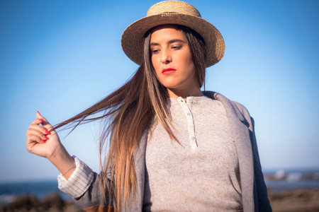 Lifestyle, portrait of a young brunette businesswoman with hat and the sea in the background