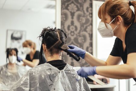 Hairdresser with mask shaving with razor. Reopening with security measures of Hairdressers in the Covid-19 pandemicの写真素材
