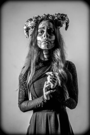 Halloween, a young woman dressed as a Mexican skull with flowers on her head. Black and white photoの写真素材