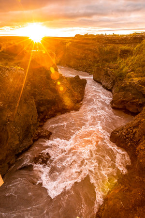 Sunset seen from the wooden bridge of the Barnafoss river, Iceland. Vertical photo