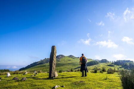 A young man in a prehistoric dolmen and in the background the top of Monte Adarra in Urnieta, near San Sebastian. Gipuzkoa, Basque Countryの写真素材