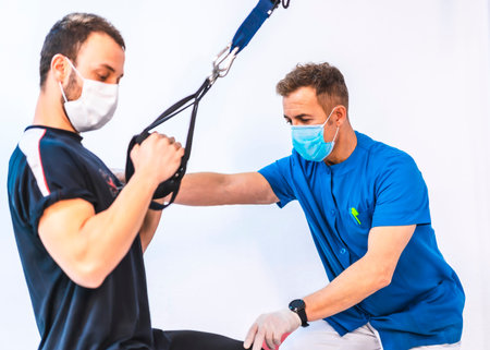 Physiotherapist in blue gown with a patient doing exercises with the arms. Physiotherapy with...