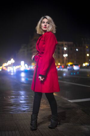 Lifestyle, a young blonde woman with a red blazer and city lights in the background in an urban sessionの写真素材