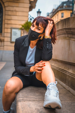 Fashion photo shoot of the new normal, a pretty young brunette with a mask on her face from the...