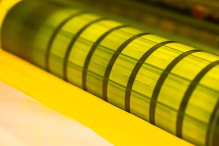 Traditional offset press. Printing in ink with CMYK, cyan, magenta, yellow and black. Graphic arts, offset printing. Detail of impression roller in offset machine of four bodies yellowの写真素材