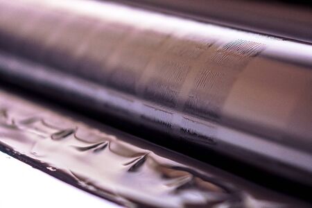 Traditional offset press. Printing in ink with CMYK, cyan, magenta, yellow and black. Graphic arts, offset printing. Offset printing roller with four bodies of black inkの写真素材