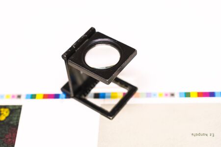 Photo session at an offset press. Printing in ink with CMYK, cyan, magenta, yellow and black. Graphic arts, offset printing. Thread counter adjustment tool on control stripsの写真素材