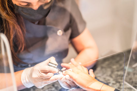 Manicure and pedicure salon, coronavirus, covid-19, social distance. The reopening due to the pandemic, security measures. Detail of a female worker behind the protective screen
