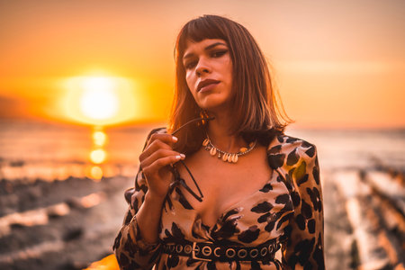 Lifestyle with sunset, a young woman in a long leopard dress on the beach of Sakoneta in the village...