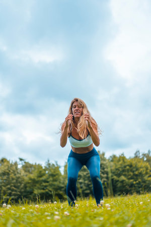 Fitness session with a young blonde caucasian woman exercising in nature with a blue maya on her...