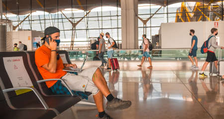 Air travel in the coronavirus pandemic, safe travel, social distance, new normal. A young man with a face mask waiting to take off, airports almost emptyのeditorial素材