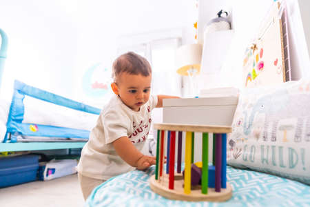 Young Caucasian mother playing with her in the room with toys. Baby less than a year learning the first lessons of her mother. Boy playing on the floor with toysの写真素材