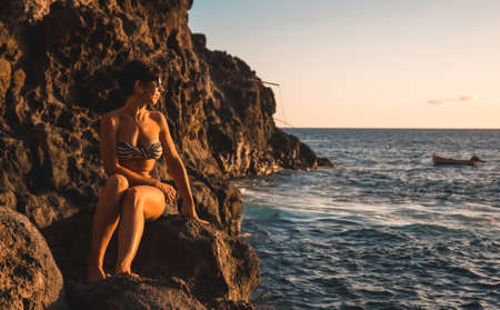 A young woman looking at the sea at sunset in the town of Poris de Candelaria on the nort-west coast of the island of La Palma, Canary Islands. Spain.の写真素材