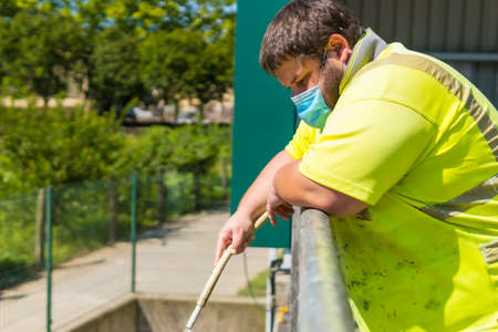 Worker in a recycling factory or clean point and garbage with a face mask and with security protections, new normal, coronavirus pandemic, covid-19. Portrait of worker cleaning with hoseの写真素材