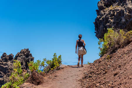 A young woman walking along the path in summer to the beach of Nogales in the east of the Island of La Plama, Canary Islands. Spainの写真素材