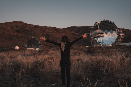 A young woman next to the new astronomical observatory of the Caldera de Taburiente at sunset, La...