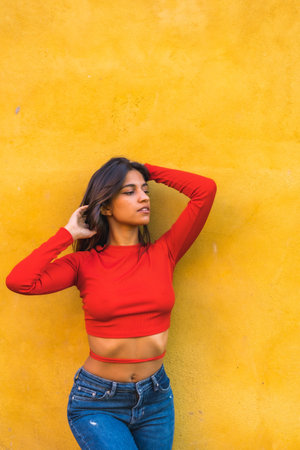 Lifestyle, young Caucasian woman in a red long-sleeved shirt. On a yellow wall background
