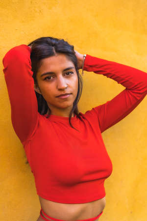 Lifestyle, young Caucasian woman in a red long-sleeved shirt. On a yellow wall backgroundの写真素材