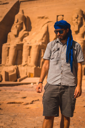 A young tourist with a blue turban visiting the Abu Simbel Temple in southern Egypt in Nubia next to...