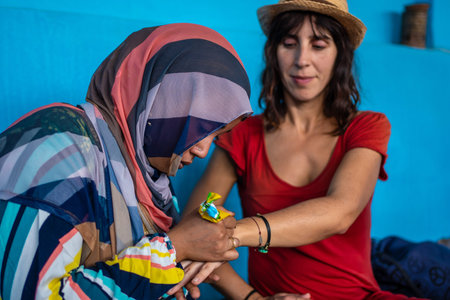 Aswan, Egypt '; October 2020: A local young woman in traditional costume, making a black gem tattoo...