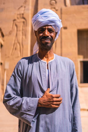 Aswan, Egypt '; October 14, 2020: A Nubian worker in a white turban guarding the beautiful Temple of Philae, a Greco-Roman construction along the Nile Riverのeditorial素材