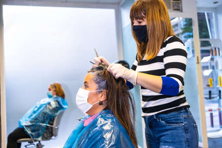 Hairdressing salon with masks on the employee and clients with the new normal working. With security measures of Hairdressers in the Covid-19 pandemic, coronavirusの写真素材