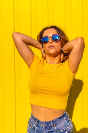 Lifestyle, Caucasian blonde girl in yellow t-shirts and short jeans on a yellow background. Fashionable posing with a smile, street photographyの写真素材
