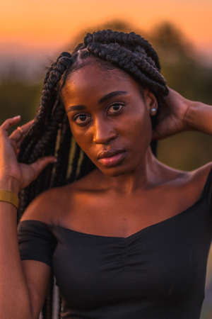 Lifestyle, Latina girl with black skin in a tight black short dress. Portrait of the young man on top of the mountain in a beautiful summer sunsetの写真素材
