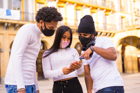 Lifestyle, Latino friends having fun with face masks looking at something on the phone. Friendships...