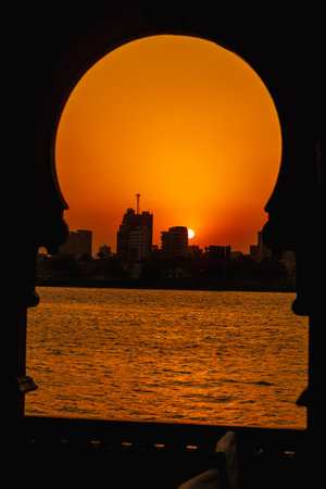 Orange sunset on the Nile river from a boat, the sun hides on the buildings of the city of Cairo in the background. Africaの写真素材