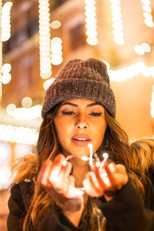 Christmas shooting with Christmas lights, Caucasian in the city at night next to Christmas lights. Elegant black christmas or new year's eve dressの写真素材