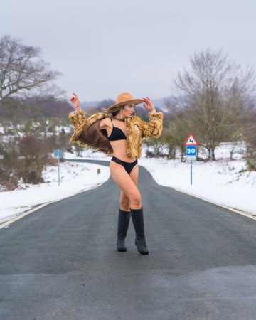 Model girl in underwear on a road, in cold conditions in the snow in a beautiful fashionable poseの写真素材