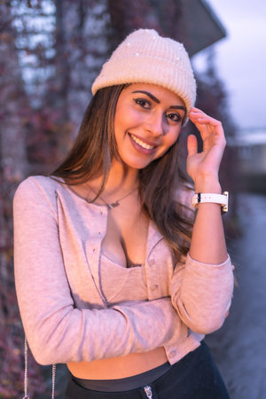 Portrait young smiling Caucasian brunette model walking in the city in winter, wearing a pink wool...
