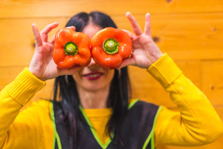 Having fun with red peppers in the hand of a brunette Caucasian fruit girl, working in a greengrocer establishmentの写真素材