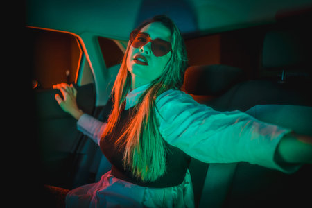Neon photography inside a car of a young blonde Caucasian woman with heart glasses