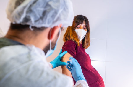 Doctor giving the new coronavirus vaccine to a young pregnant woman. Antibodies, they immunize the...