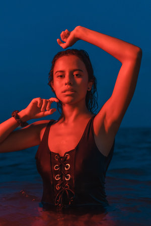 Lifestyle of a young pretty brunette Caucasian posing bathing at night in the sea with an...