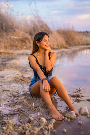A young brunette Caucasian on vacation in the pink lagoon of Torrevieja in summer, wearing jeans and a black t-shirtの写真素材