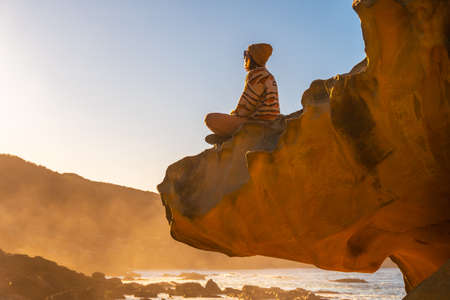 Yoga at sunset in the cove of stones in the Jaizkibel mountain in the town of Pasajes, Gipuzkoa. Basque Countryの写真素材