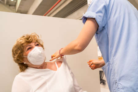 San SebastiÃ¡n, Gipuzkoa. Spain. May 8, 2021: An adult woman receiving the prick of the Pfizer dose by a young nurse at the Illumbe vaccination center, covid-19. Coronavirusのeditorial素材