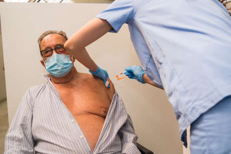San SebastiÃ¡n, Gipuzkoa. Spain. May 8, 2021: An adult male receiving the jab of the Pfizer dose by a young nurse at the vaccination center, covid-19. Coronavirusのeditorial素材