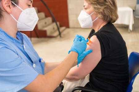 San SebastiÃ¡n, Gipuzkoa. Spain. May 8, 2021: A lady receiving the injection of the dose by a young nurse at the vaccination center, covid-19. Coronavirusのeditorial素材