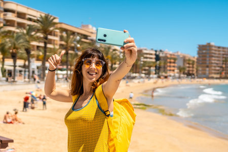 A young tourist taking a selfie with the phone at Playa del Cura in the coastal city of Torrevieja,...