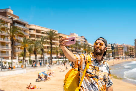 A young tourist with the phone on Playa del Cura in the coastal city of Torrevieja, Alicante, Valencian Community. Spain, Mediterranean Seaの写真素材