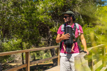 A young father with his son in his backpack on the path to Playa Moncayo on the Mediterranean Sea in Guardamar del Segura next to Torrevieja, Alicante. Community of Valencia. Spainの写真素材